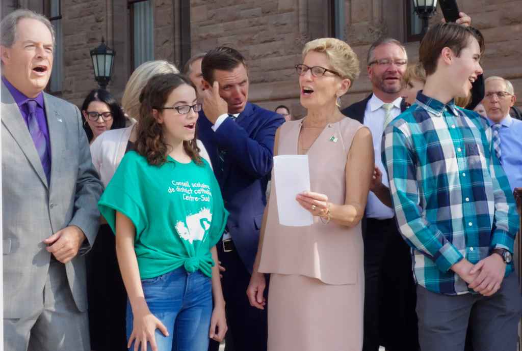 La Première ministre de l'Ontario Kathleen Wynne, les deux élèves conseillés et le président de l'Assemblée de la Francophonie de l'Ontario Carol Jolin hissent le drapeau franco-ontarien en entonnant l'hymne des Franco-Ontariens et Franco-Ontariennes "Notre Place"